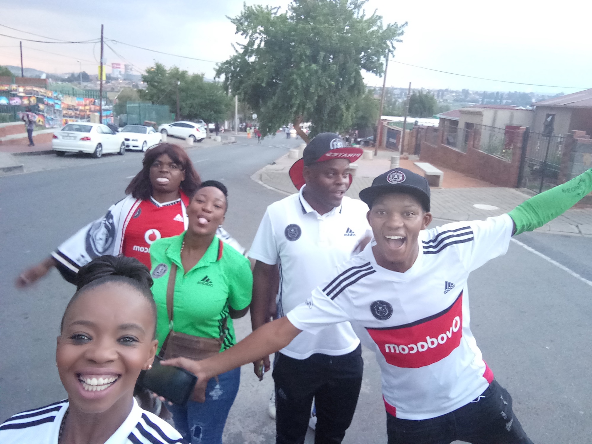 Orlando Pirates supporters in club kit celebrating in the streets of Soweto